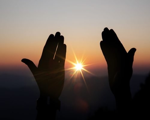 Faith of christian concept: Spiritual prayer hands over sun shine with blurred beautiful sunset background